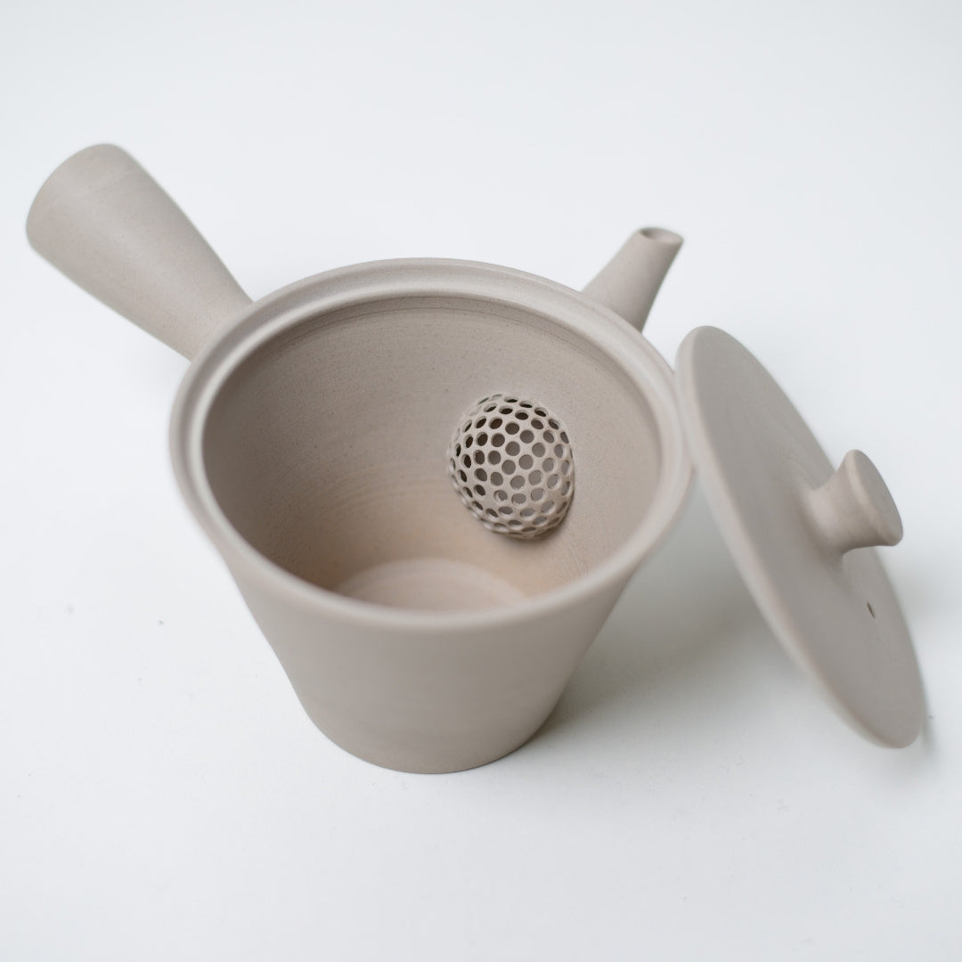 Open hvid kyusu japansk tekande, der afslører den indbyggede keramiske mesh-si inde i den uglaseret ler krop.