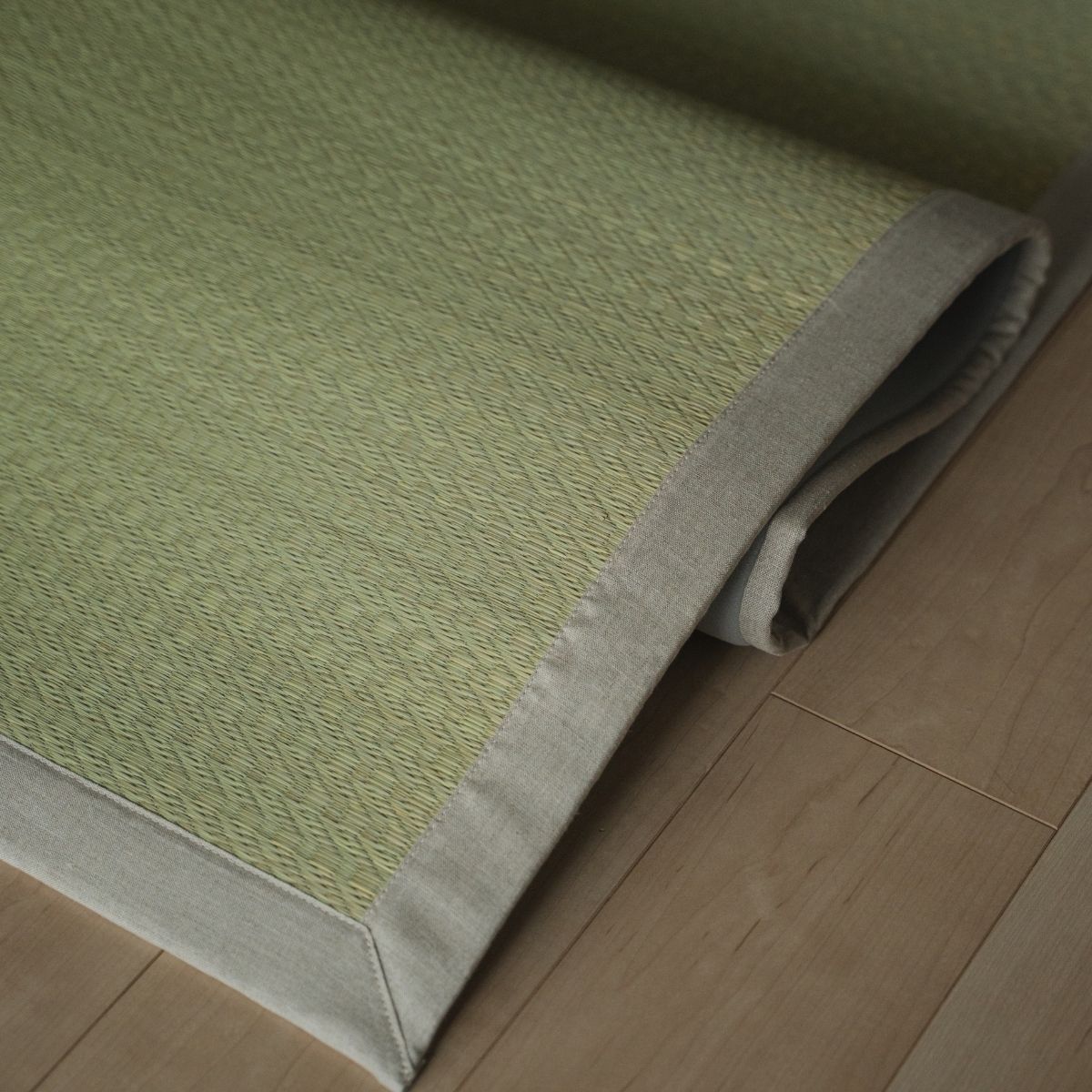 Japanese natural rush tatami area rug folded on a wood floor, offering a smooth texture for minimalist Japanese decor.