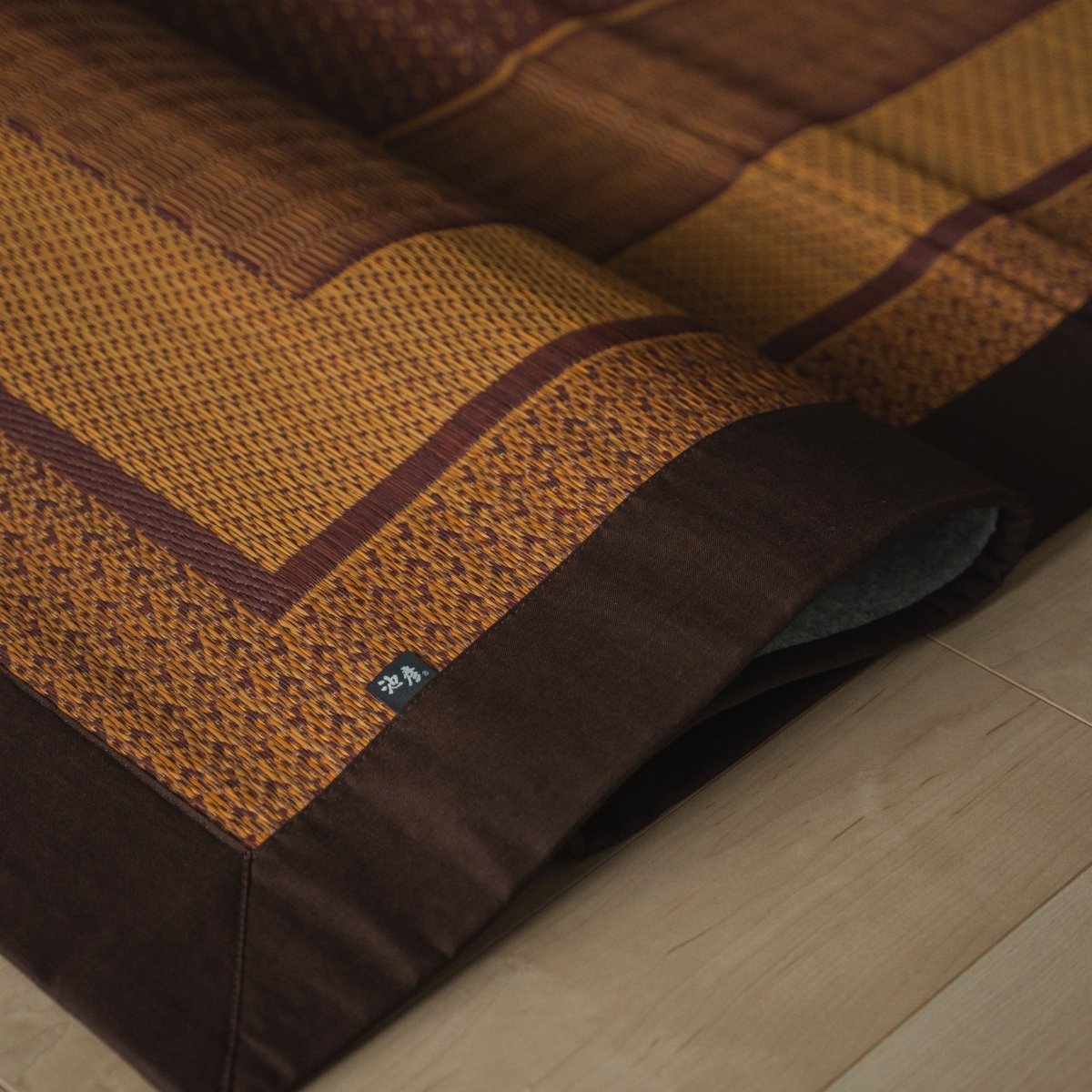Japanse bordeauxrode tatami vloerkleed opgevouwen op een houten vloer, met een elegant patroon voor Japanse decoratie.