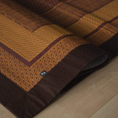 Japanse bordeauxrode tatami vloerkleed opgevouwen op een houten vloer, met een elegant patroon voor Japanse decoratie.