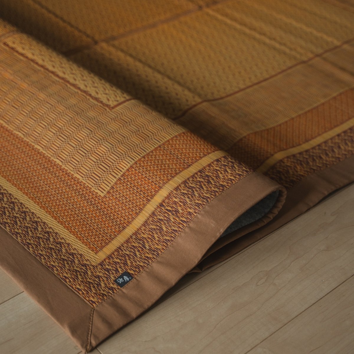 Japanse natuurlijke beige rieten tatami vloerkleed opgevouwen op een houten vloer, met een geometrisch patroon voor Japanse decoratie.