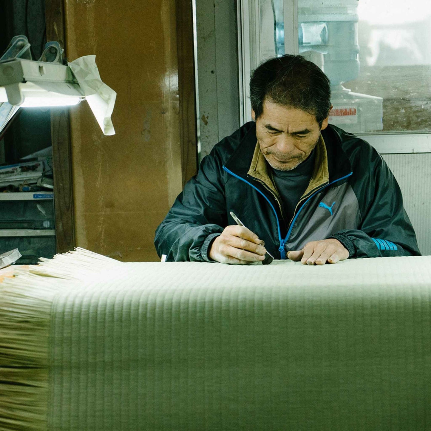 Japansk håndværker, der dygtigt fremstiller en traditionel tatami-måtte i et værksted, der bevarer historien.