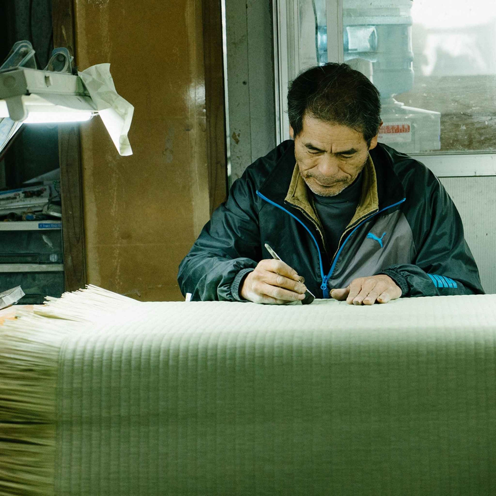Japansk håndværker, der dygtigt fremstiller en traditionel tatami-måtte i et værksted, der bevarer historien.