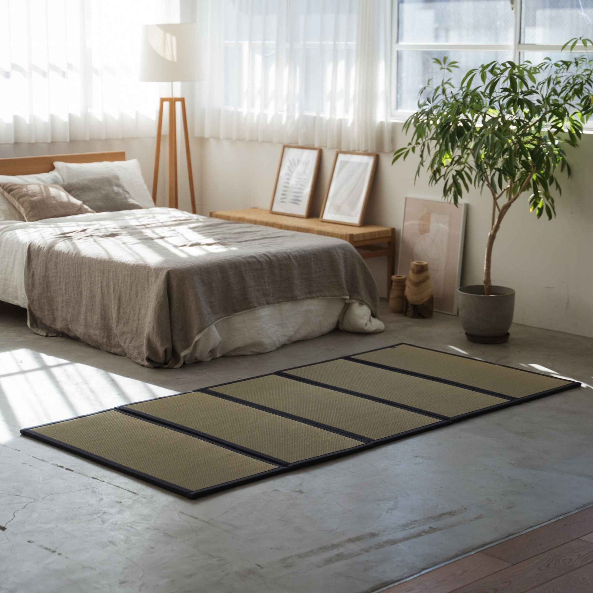 Vijf panelen tatami matras op een betonnen slaapkamervloer die dient als ademende en gezonde basis voor een futon.