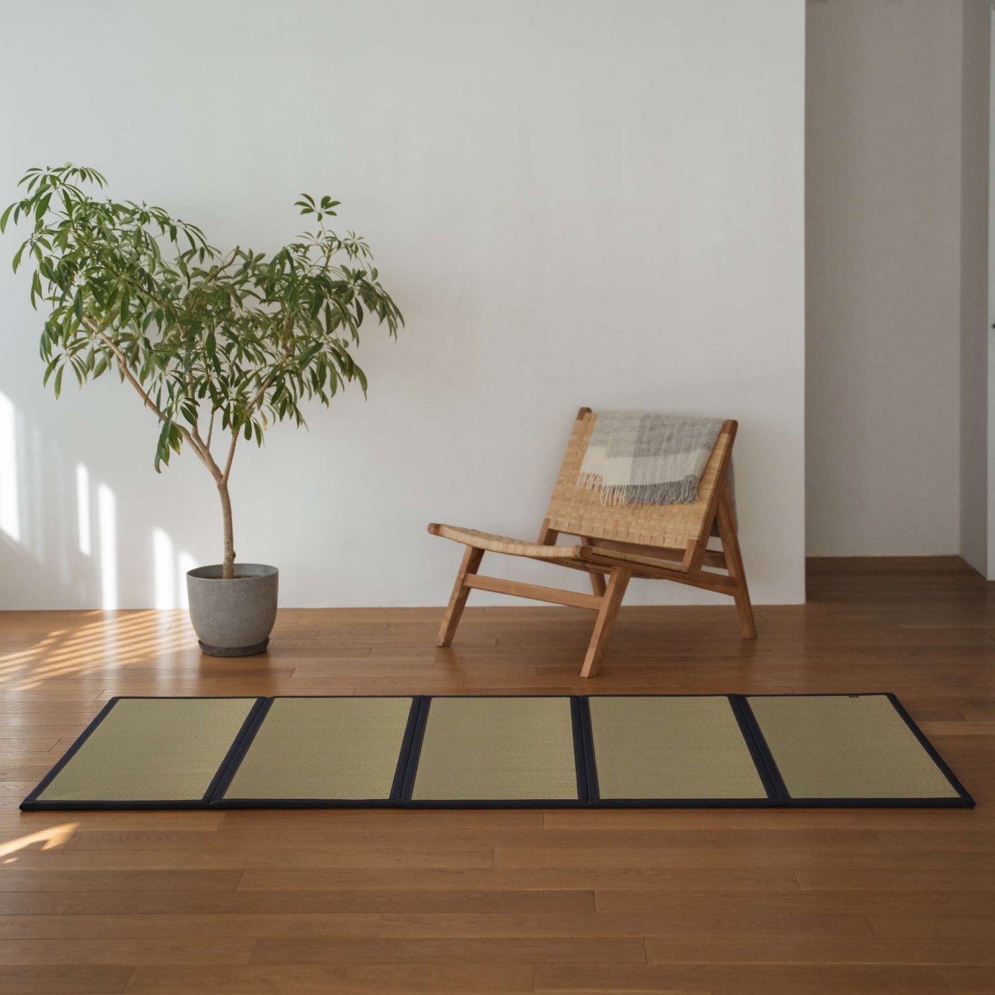 Vijfdelige onverfde tatamimat gelegd op een houten woonkamervloer, wat zorgt voor een soepele en natuurlijke zen-decoratie.