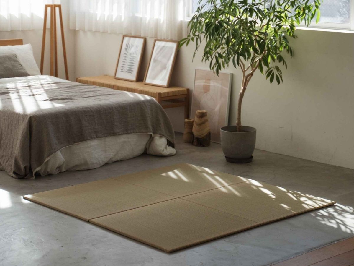 Quadratische Tatami-Matten, die als Teppich auf einem Betonboden im Schlafzimmer ausgelegt sind und einen ruhigen Meditationsbereich definieren.
