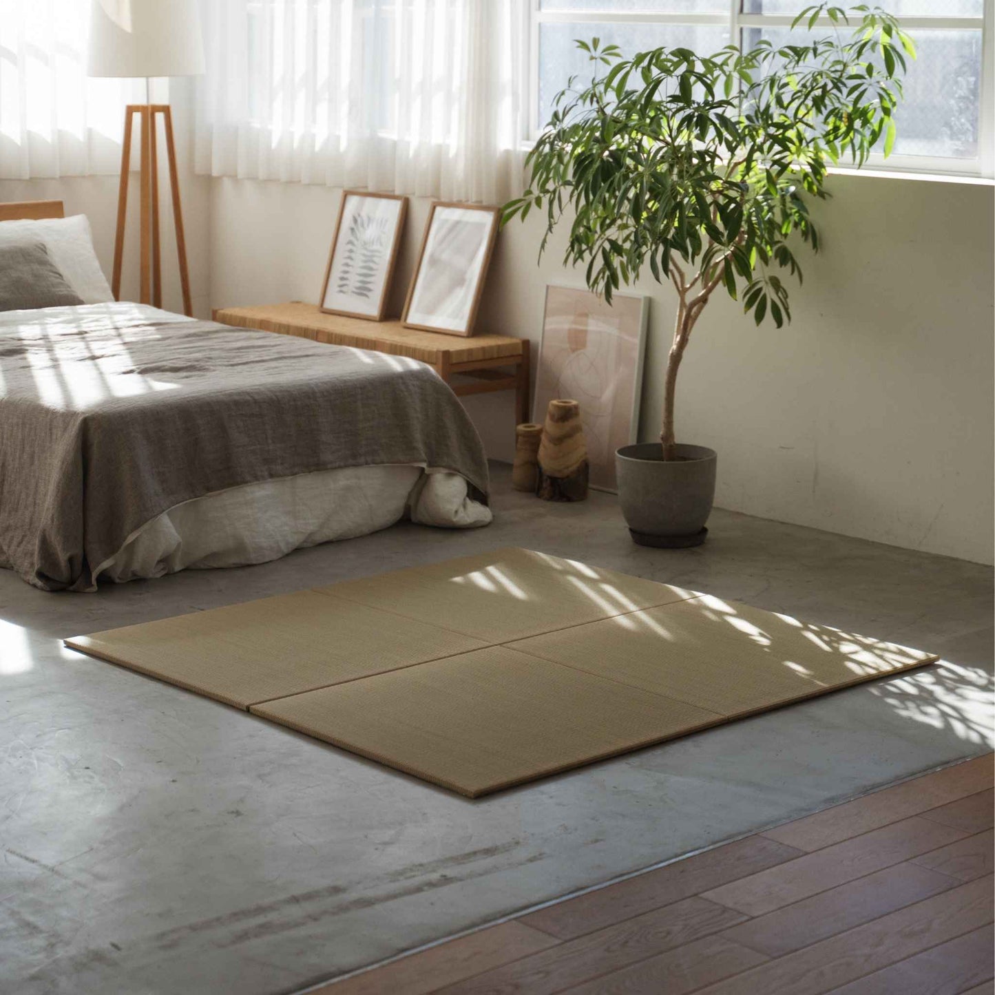 Quadratische Tatami-Matten, die als Teppich auf einem Betonboden im Schlafzimmer ausgelegt sind und einen ruhigen Meditationsbereich definieren.