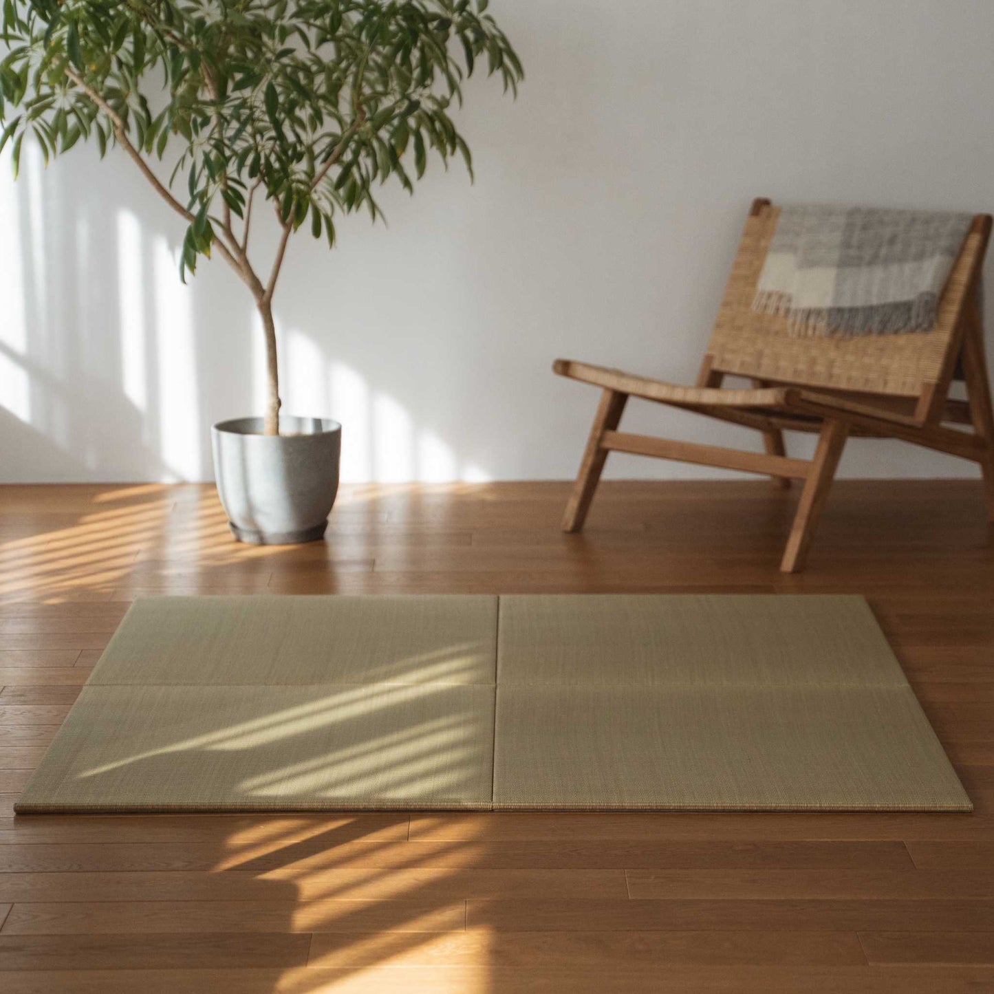 Vier quadratische Tatami-Matten-Paneele, die auf einem Holzboden im Wohnzimmer ausgelegt sind und eine natürliche Zen-Dekorationsecke bilden.