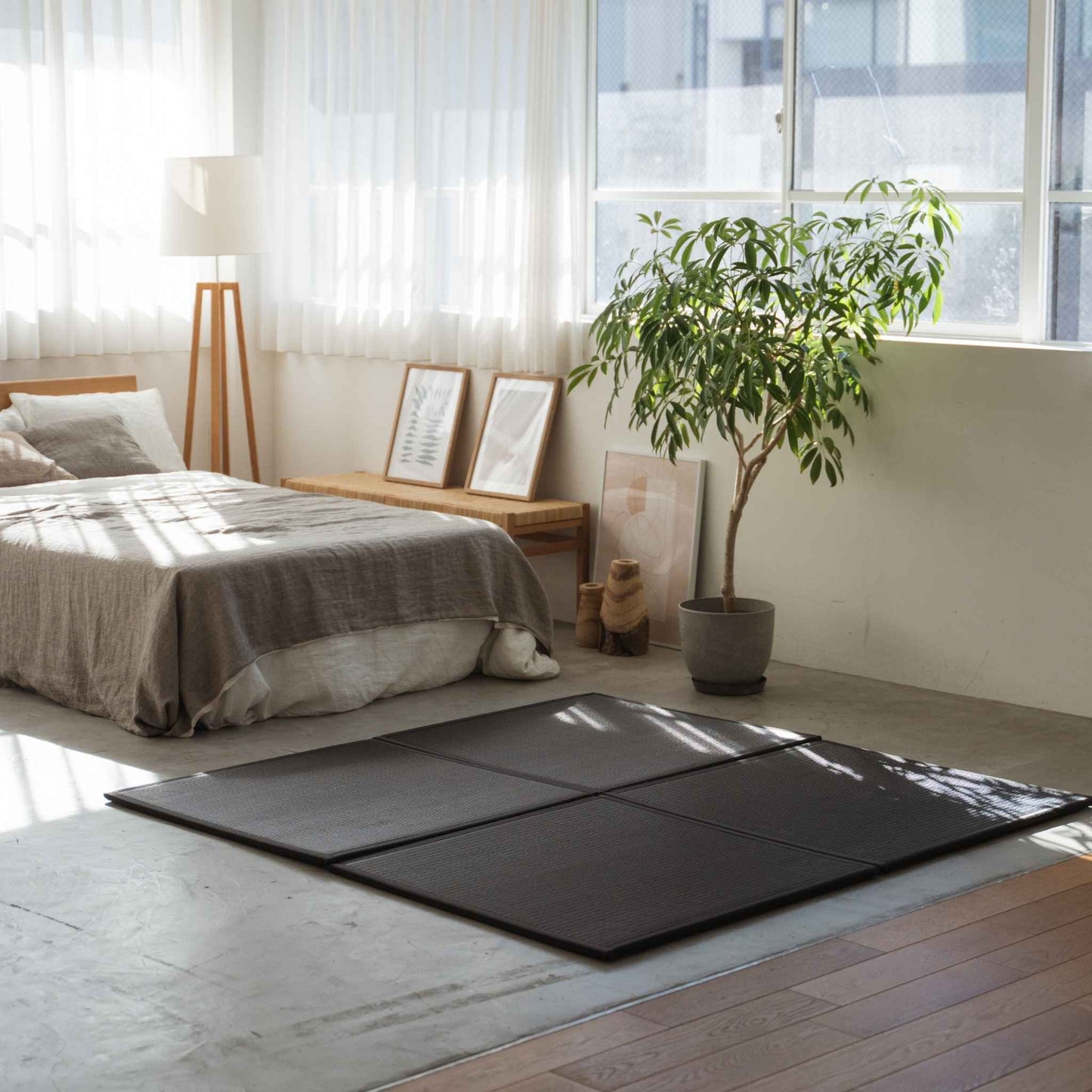 Schwarze quadratische Tatami-Matten auf einem Betonboden im Schlafzimmer, die eine stilvolle und fleckenresistente Meditationsecke bilden.