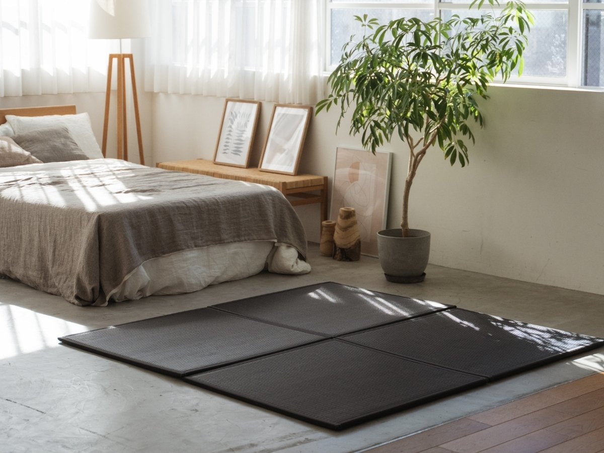 Schwarze quadratische Tatami-Matten auf einem Betonboden im Schlafzimmer, die eine stilvolle und fleckenresistente Meditationsecke bilden.