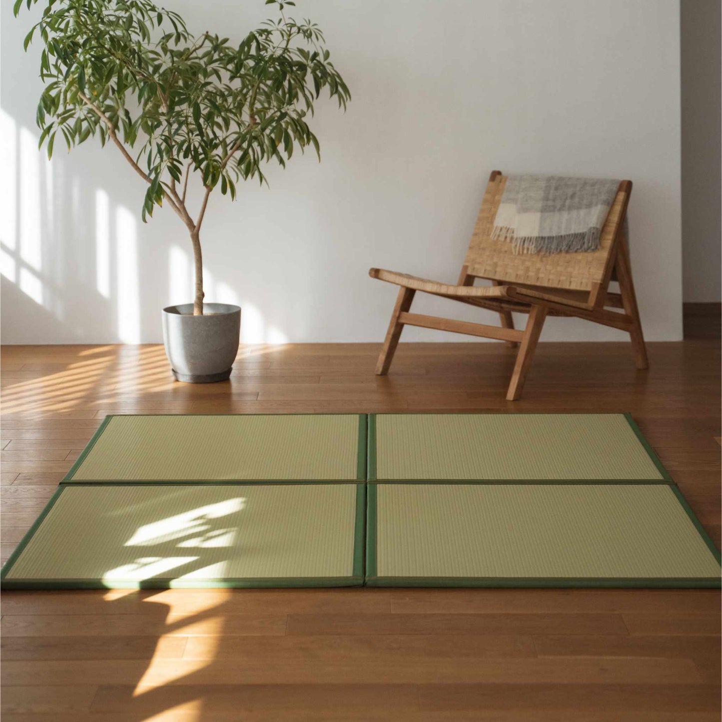 Vier groene vierkante tatamimatten op een houten woonkamervloer die dienen als een duurzaam zen vloerkleed.