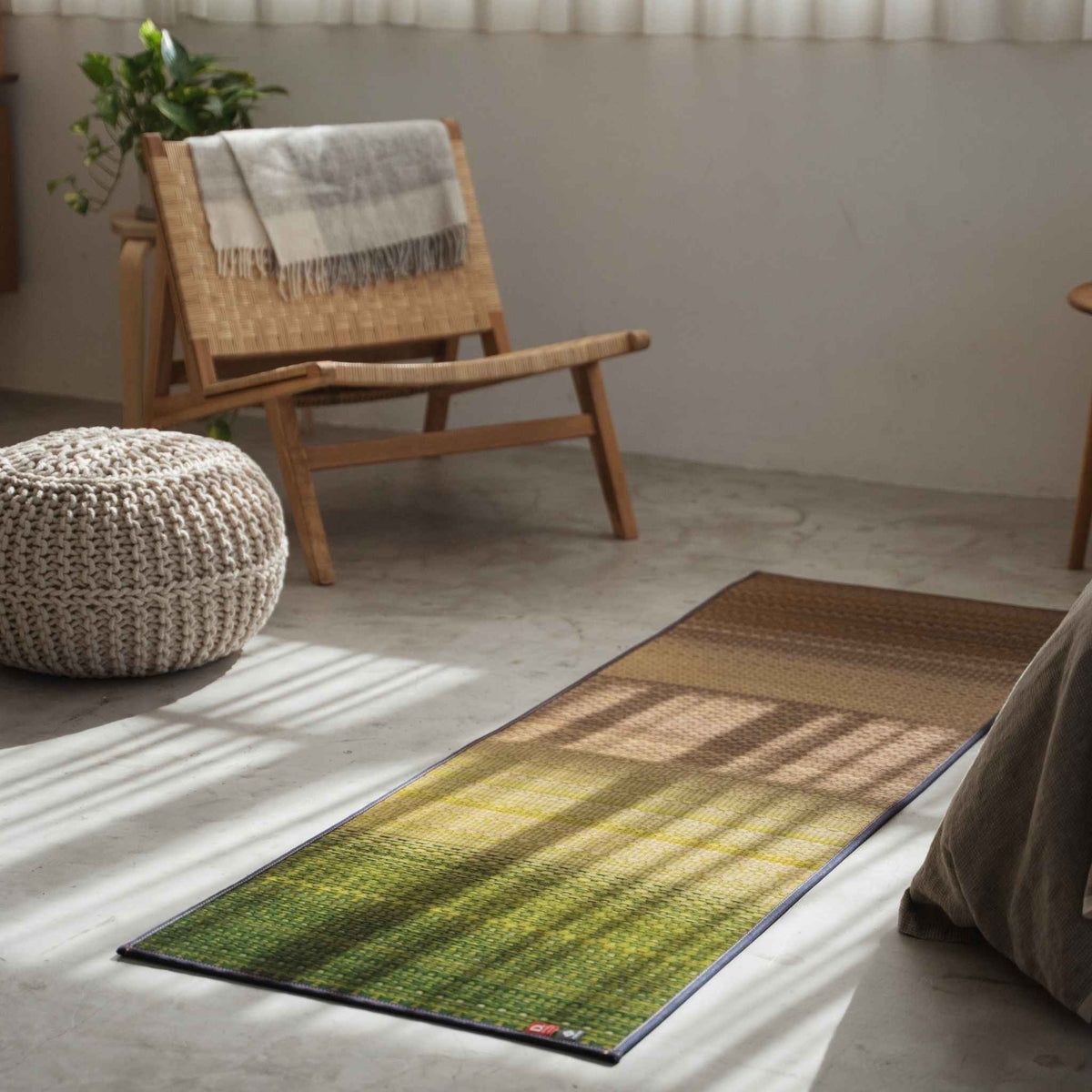 Groene tatami yogamat op een betonnen vloer naast een stoel, met een zen-decor voor wellness.