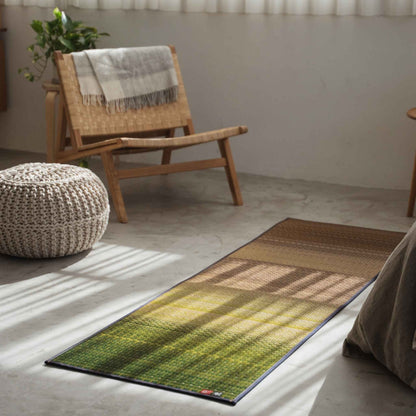 Grøn tatami yogamåtte lagt på et betongulv ved siden af en stol, der tilbyder en zen-indretningsstemning til velvære.
