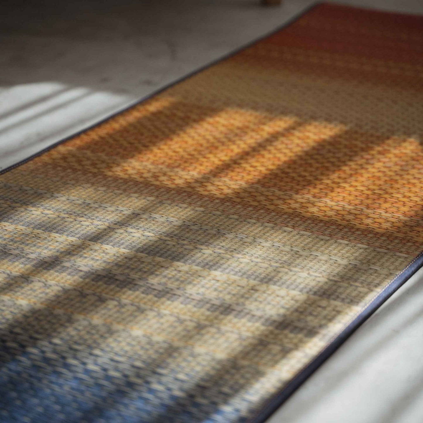 Schräge Ansicht einer japanischen Tatami-Yogamatte mit einem wunderschönen roten Farbverlauf auf dem Boden.