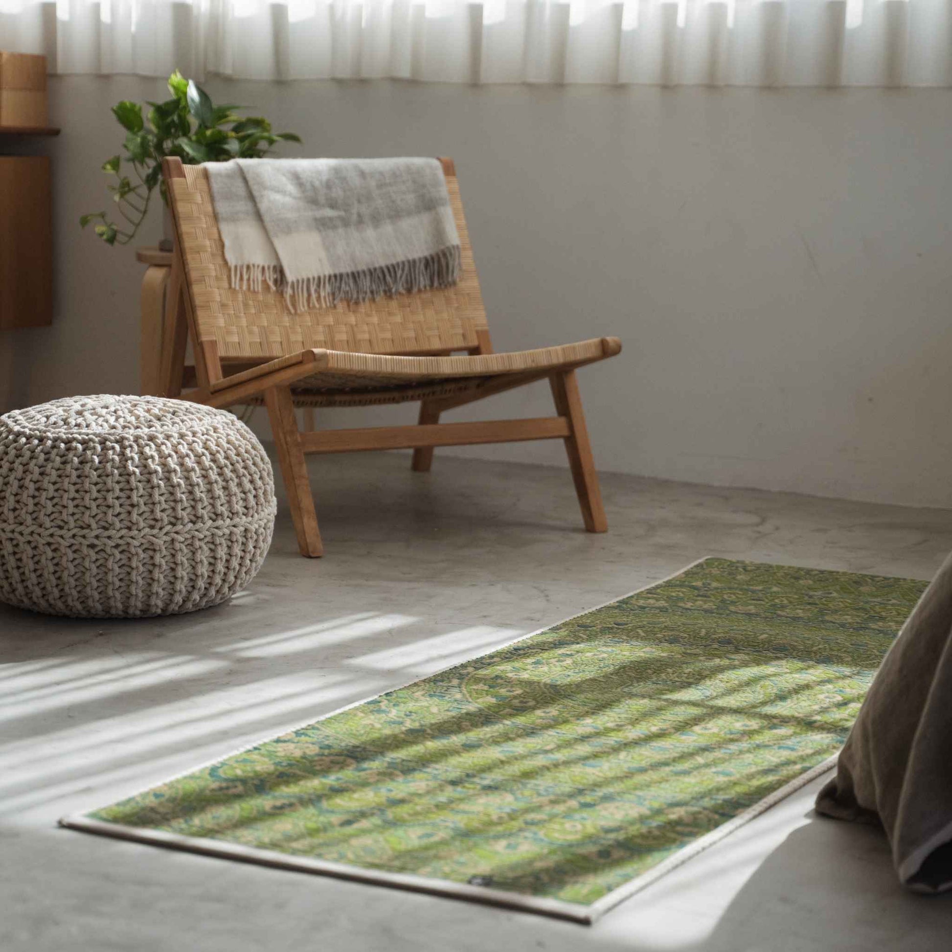 Grüne Mandala-Tatami-Matte auf einem Betonboden im Wohnzimmer, die einen ruhigen Meditationsraum schafft.