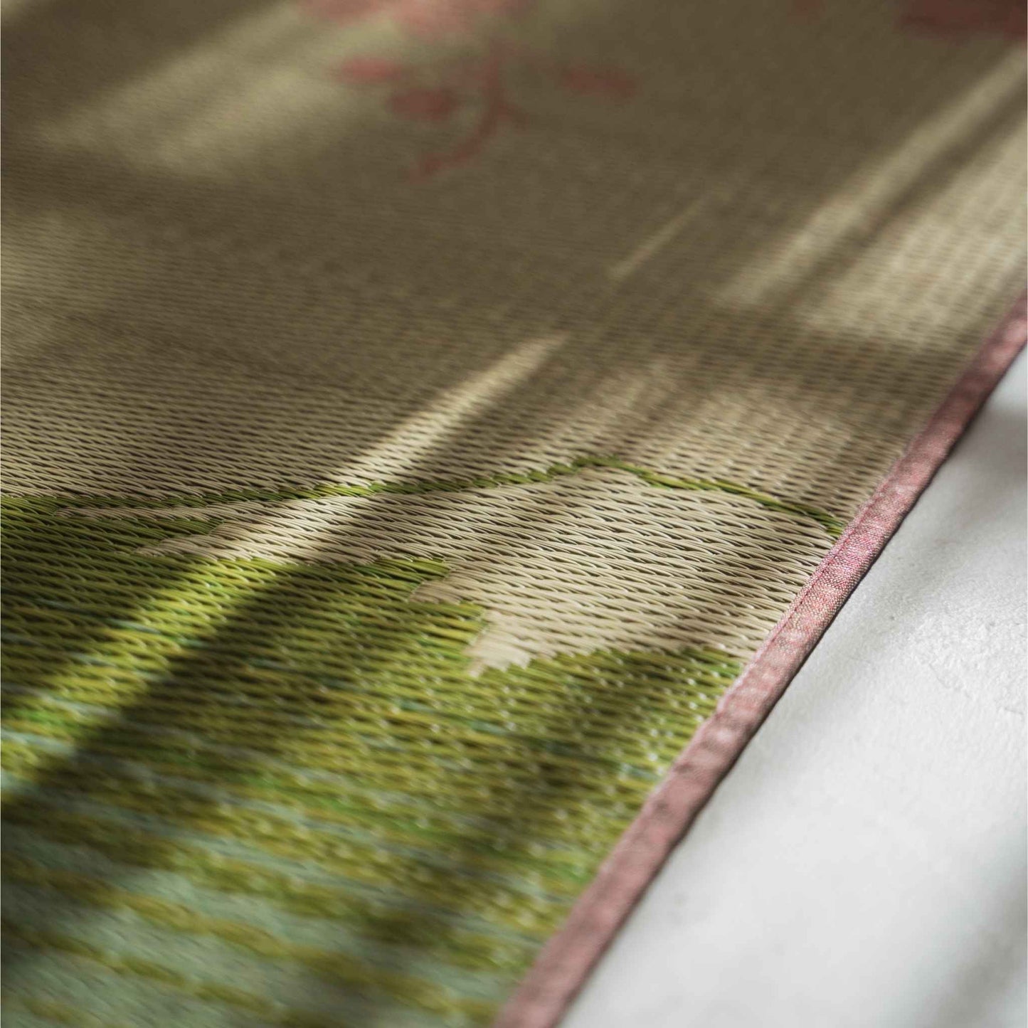 Close-up van de textuur van biesgras op een tatamimat met een ingewikkeld roze sakura-weefpatroon.