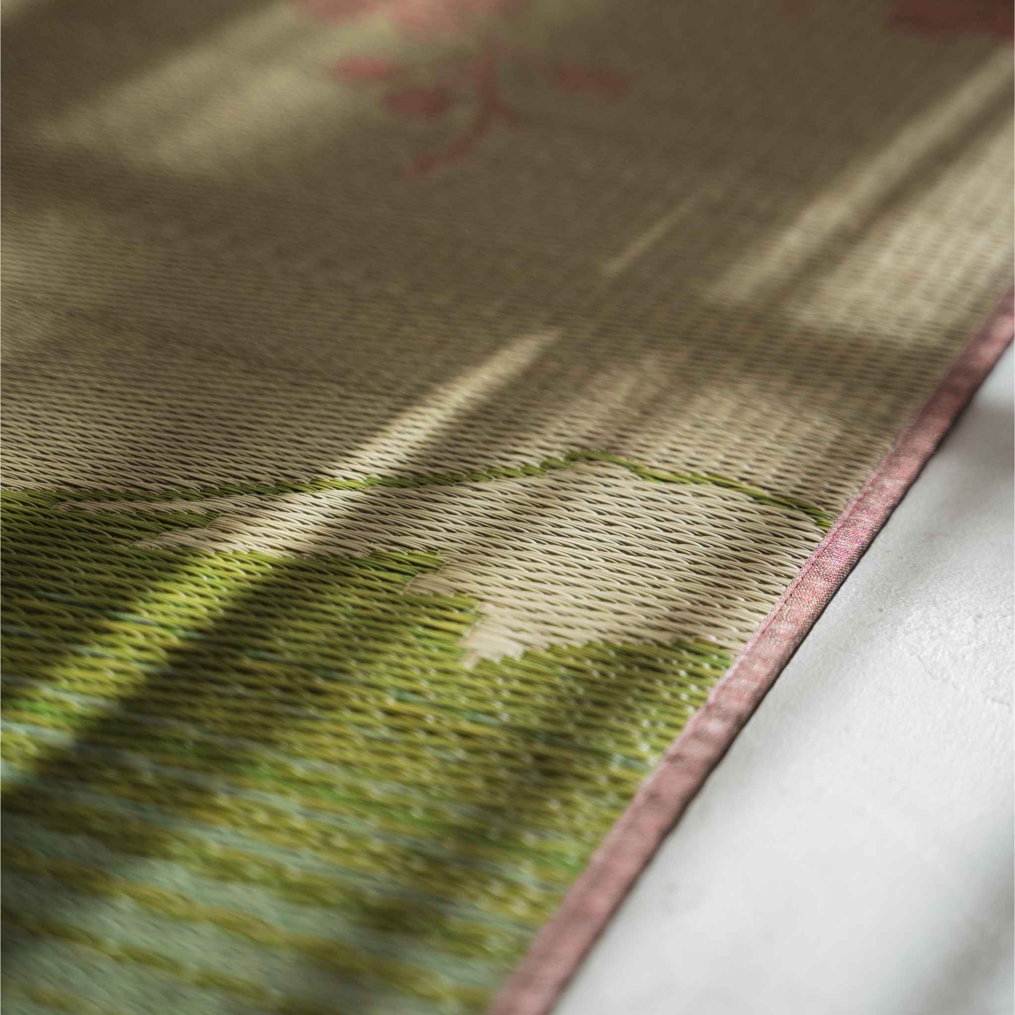 Close-up van de textuur van biesgras op een tatamimat met een ingewikkeld roze sakura-weefpatroon.