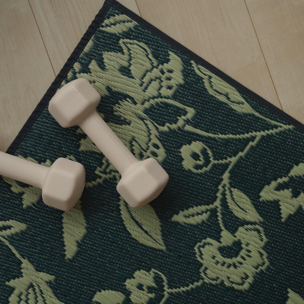 An overhead view of the Japanese Tatami Yoga Mattress "Sarasa" Navy with a small pink dumbbell, highlighting its botanical motif.