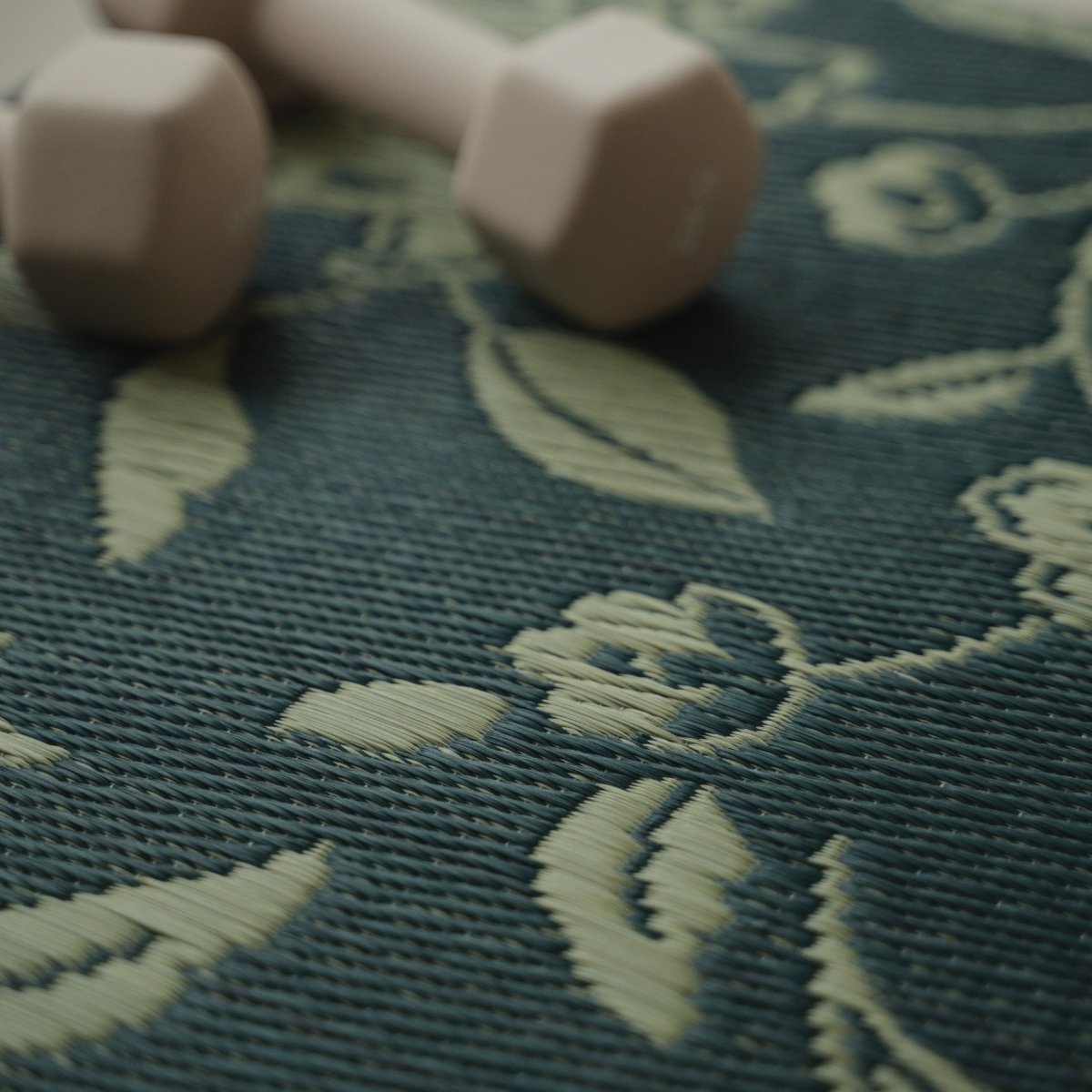 A close-up of the intricate botanical motif on a Japanese Tatami Yoga Mattress "Sarasa" Navy with a dumbbell.