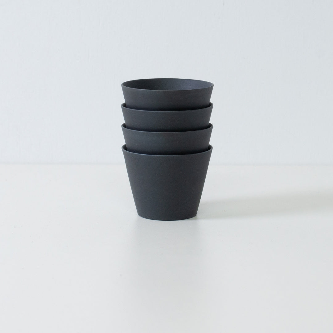 Stabel af fire sorte japanske ensui-tekopper, der viser det pladsbesparende design i dette moderne stentøjssæt