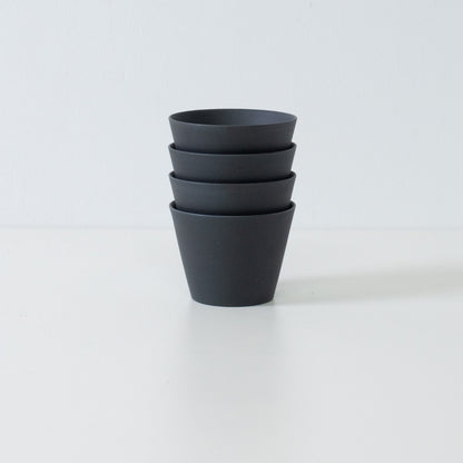 Stabel af fire sorte japanske ensui-tekopper, der viser det pladsbesparende design i dette moderne stentøjssæt