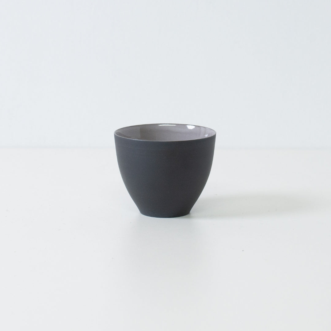 Sidevisning af matsorte japanske tekopper f-form chawan stående på hvid overflade med moderne banko-keramik silhuet