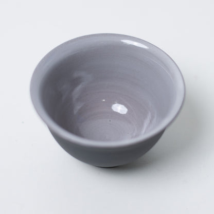 Top-down-udsigt inde i en kumidashi japansk tekop, der viser en blank grå glasurtekstur mod en sort lerfælge.
