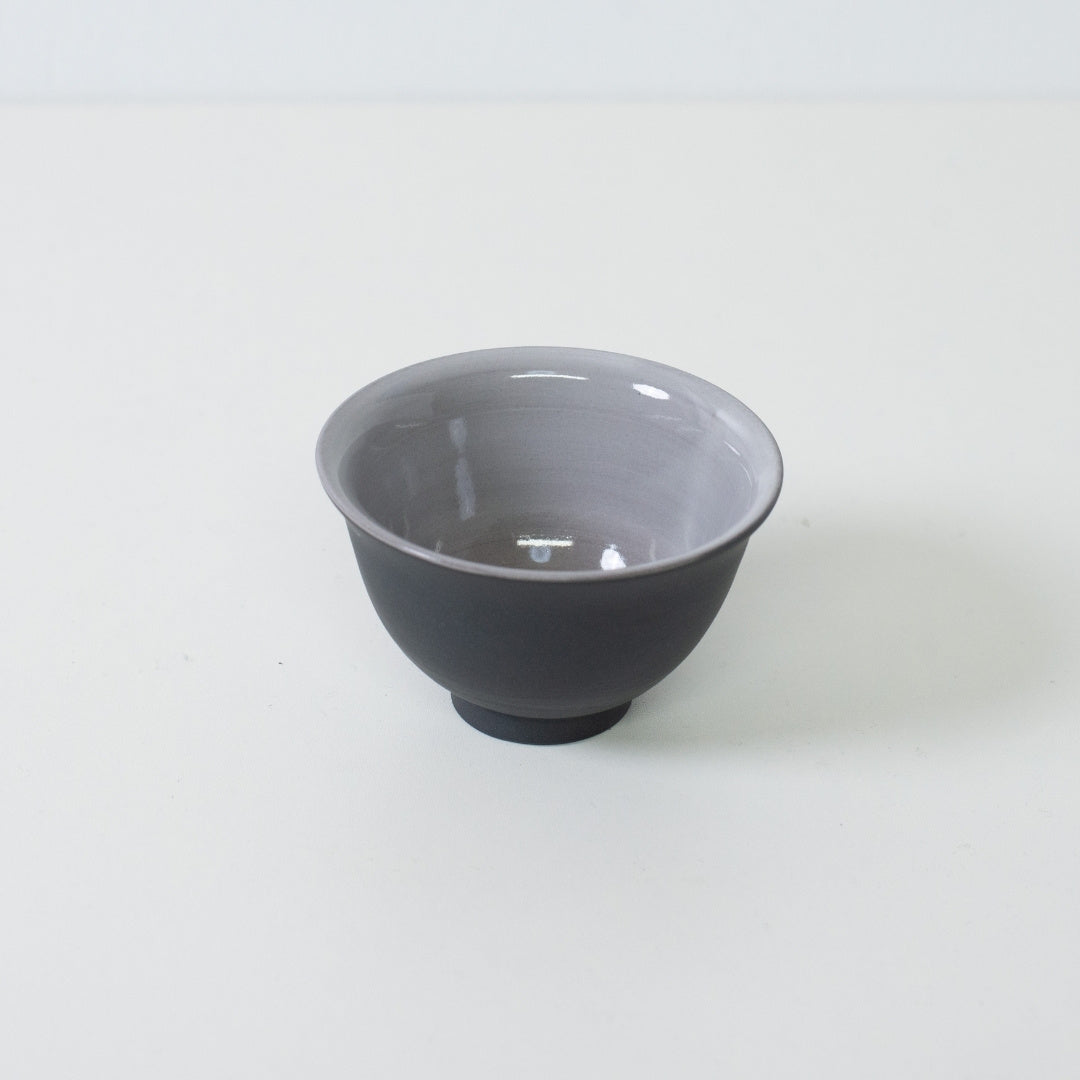 Vinklet billede af sort japansk tekop, der afslører gråglaseret indre designet til at fremhæve tefarven.