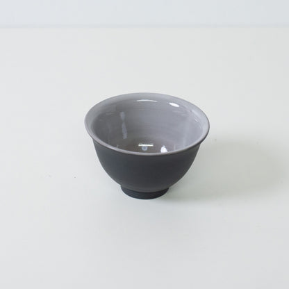 Vinklet billede af sort japansk tekop, der afslører gråglaseret indre designet til at fremhæve tefarven.