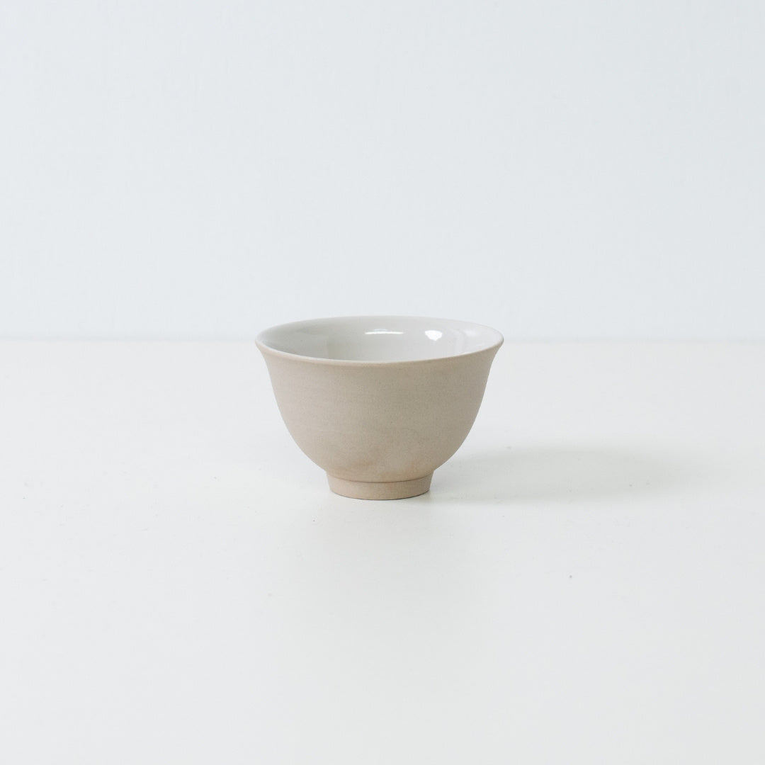 Profilvisning af en enkelt beige kumidashi japansk tekop med en mat stentekstur