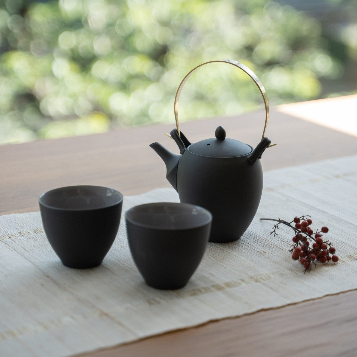 Traditionelt sort japansk tesæt på et solbeskinnet bord til gæster, der oplever autentisk gæstfrihed.
