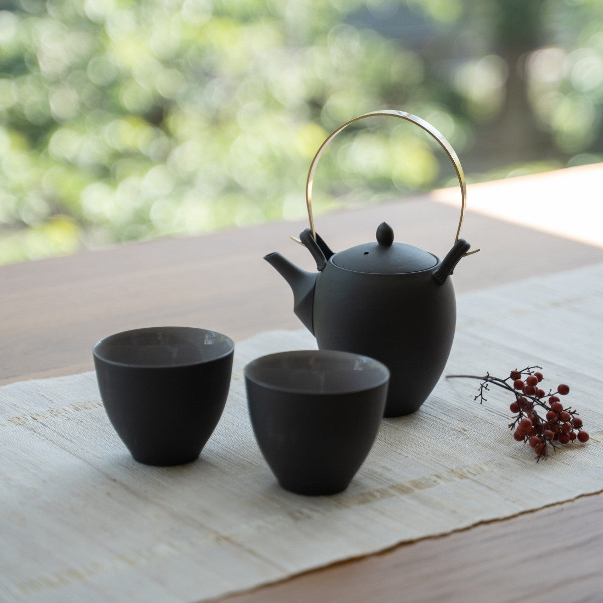 Service à thé japonais noir avec kyusu sur une table en bois pour les amateurs de thé profitant d'un rituel zen moderne.