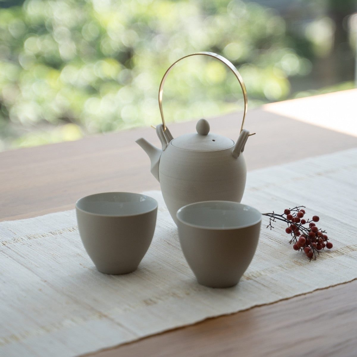 Théière japonaise blanche "Donguri" et tasses à thé japonaises sur une table pour les adeptes du bien-être qui embrassent un rituel zen moderne.