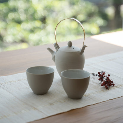 Théière japonaise blanche "Donguri" et tasses à thé japonaises sur une table pour les adeptes du bien-être qui embrassent un rituel zen moderne.