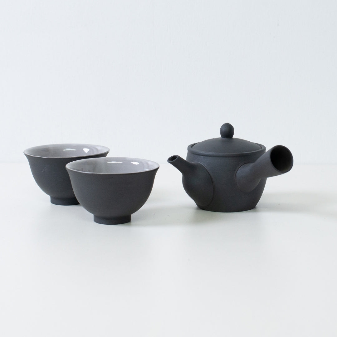 Sort japansk tesæt med fuyo kyusu tekande og kumidashi kopper arrangeret på hvid overflade til servering.