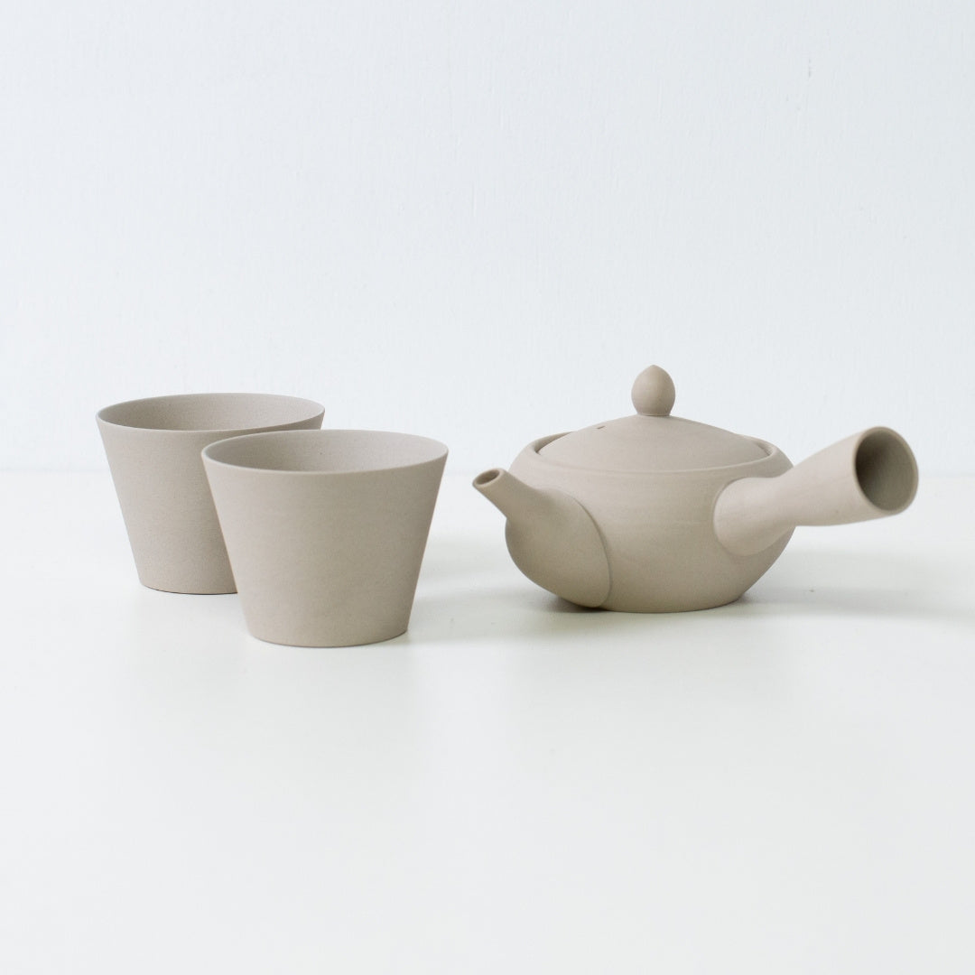 Bleg hvidt japansk tesæt med en munkeskål, kyusu tekande og matchende tekopper med stenstruktur.