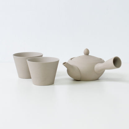 Bleg hvidt japansk tesæt med en munkeskål, kyusu tekande og matchende tekopper med stenstruktur.