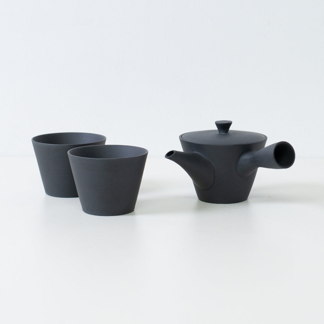 Japansk tesæt med en sort sencha kyusu tekande og to matte ensui chawan tekopper placeret på et hvidt bord.