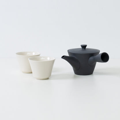 Japansk tesæt med en sort kyusu tekande ved siden af to hvide, krakelerede kodai tekopper til gæstfrihed.