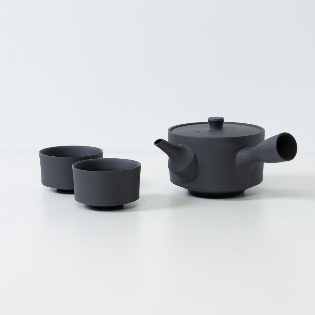 Matte sort japansk tesæt med en 350cc sencha kyusu og minimalistiske cylinder chawan-kopper på et hvidt bord