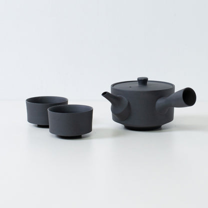 Matte sort japansk tesæt med en 350cc sencha kyusu og minimalistiske cylinder chawan-kopper på et hvidt bord