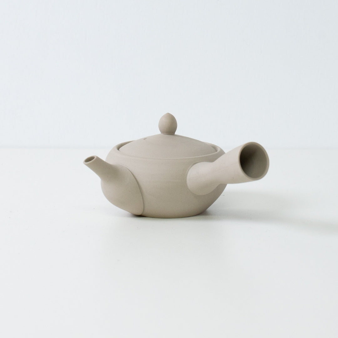 Minimalistisk hvid japansk tekande i munke-skål form lavet af uglaseret ler på en ren hvid overflade.