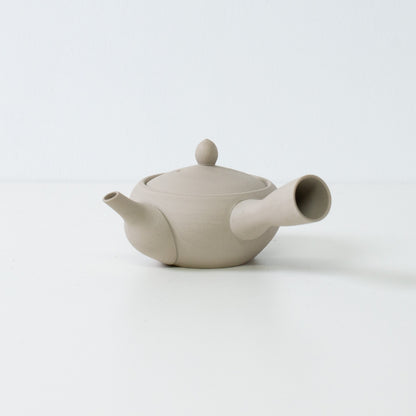 Minimalistisk hvid japansk tekande i munke-skål form lavet af uglaseret ler på en ren hvid overflade.