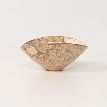 "Un bol kintsugi blanc fait à la main se dresse sur une table, exposant des lignes dorées d'art de poterie authentique"