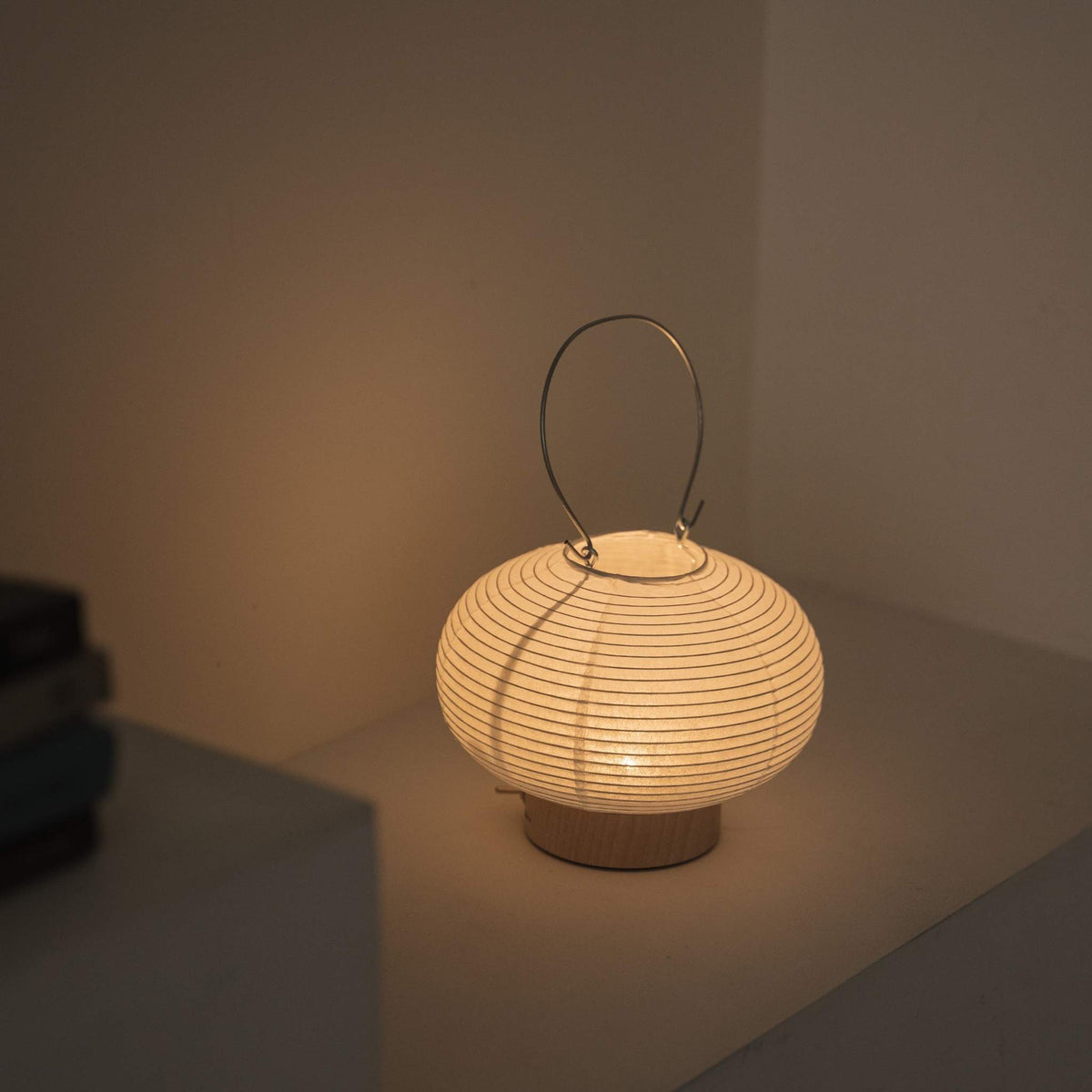 Overhead view of a lit portable lamp made of mino washi paper highlighting the ribbed structure and warm light