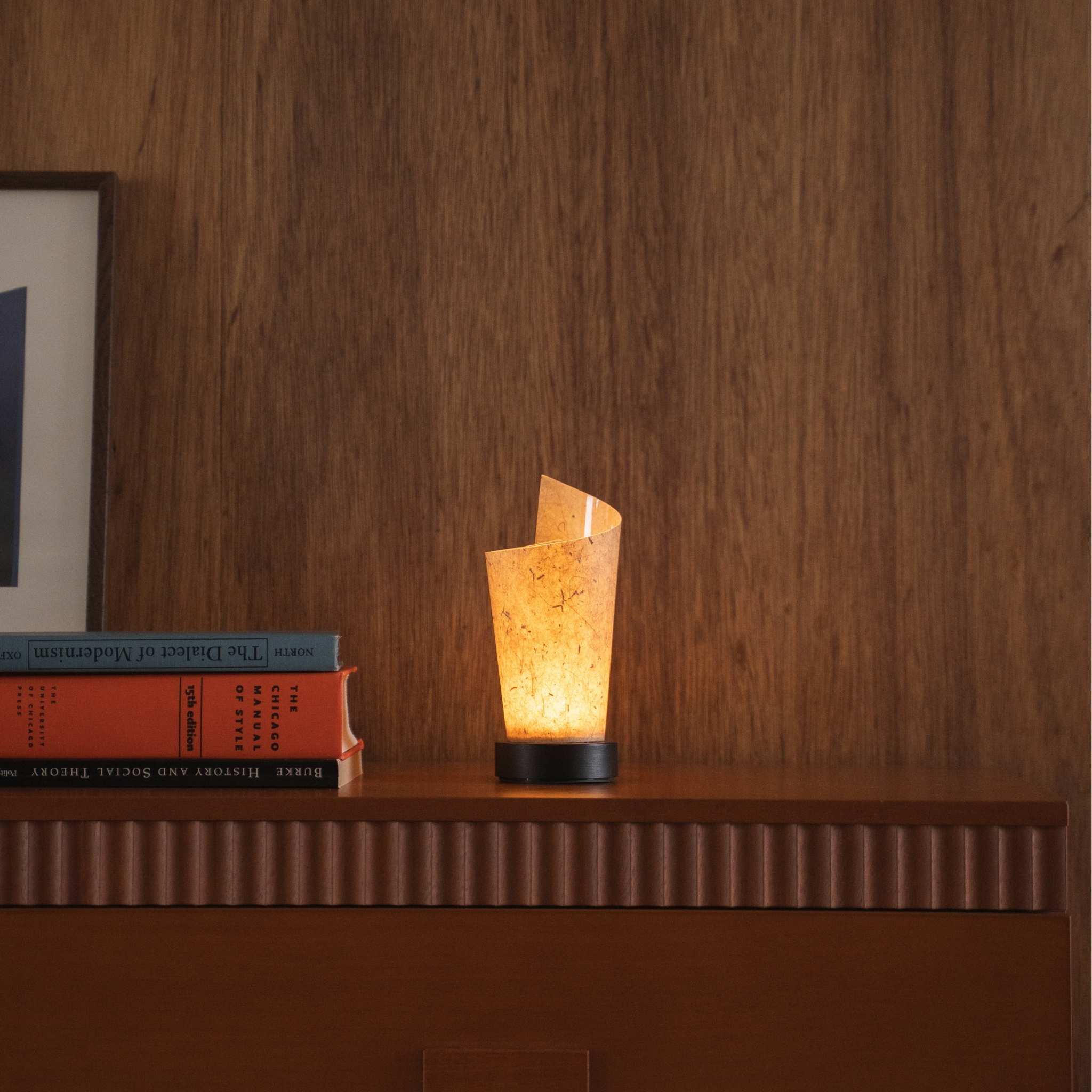 "Lampe de table japonaise en papier "Maki" avec écorce de cèdre projetant une lumière douce vers le haut comme lampe d'ambiance sur une console de style mid-century modern."