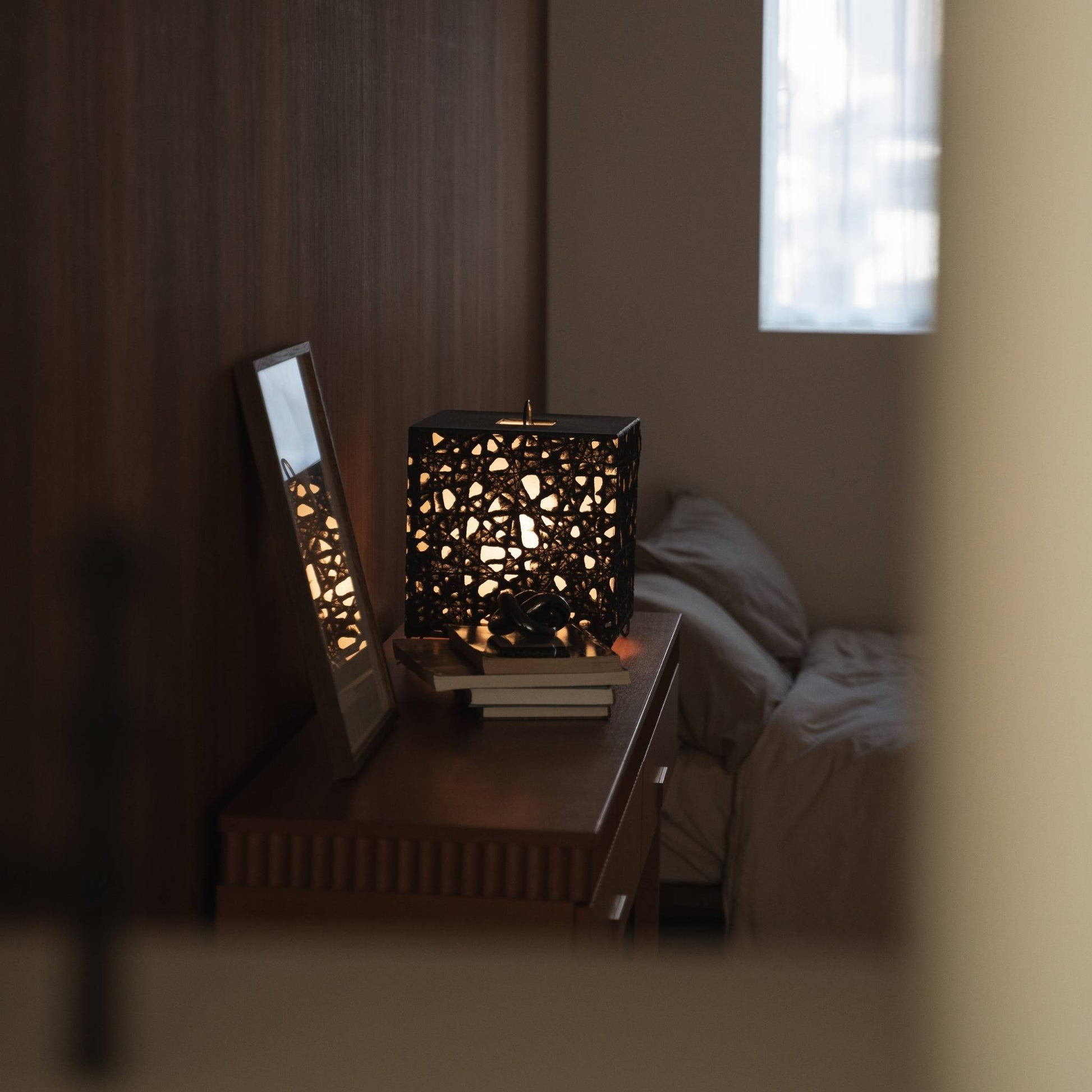 "Cube lumineux en papier japonais Me Look 03 servant de lumière d'appoint sur une console en bois avec décoration."