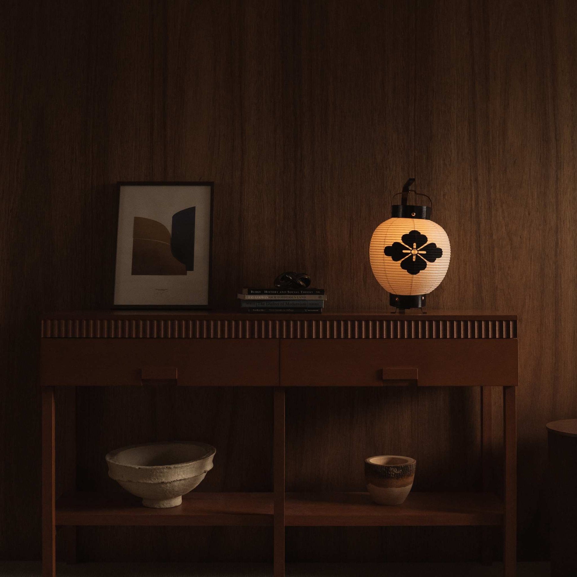 Kleine Japanse papieren lantaarn die op een mid-century modern dressoir staat in een schemerige woonkamer