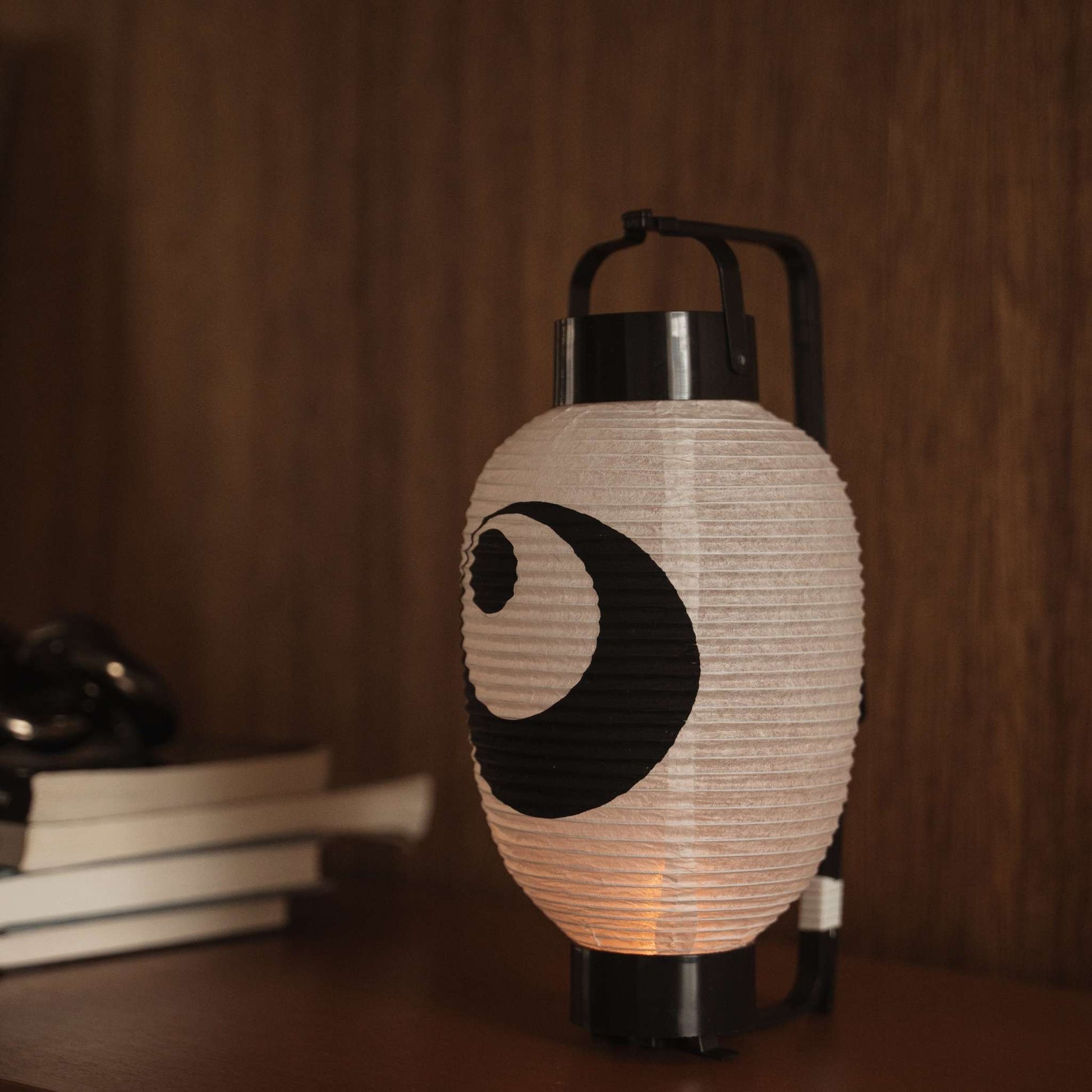 Lit Japanse papieren lantaarn chochin op een donkere houten tafel met het traditionele zwart-inktontwerp.