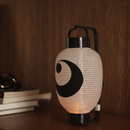 Lit Japanse papieren lantaarn chochin op een donkere houten tafel met het traditionele zwart-inktontwerp.